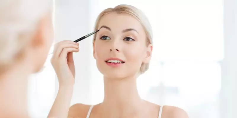 Girl drawing on eyebrows